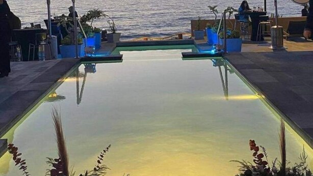 Una piscina con vista sul mare al tramonto.