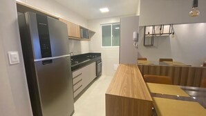 Une cuisine moderne dotée d’appareils électroménagers en acier inoxydable, de meubles en bois et d’un coin repas avec une table et des chaises en verre.