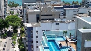 Un immeuble de grande hauteur doté d’une piscine sur le toit, de nombreux balcons et offrant une vue sur l’océan.