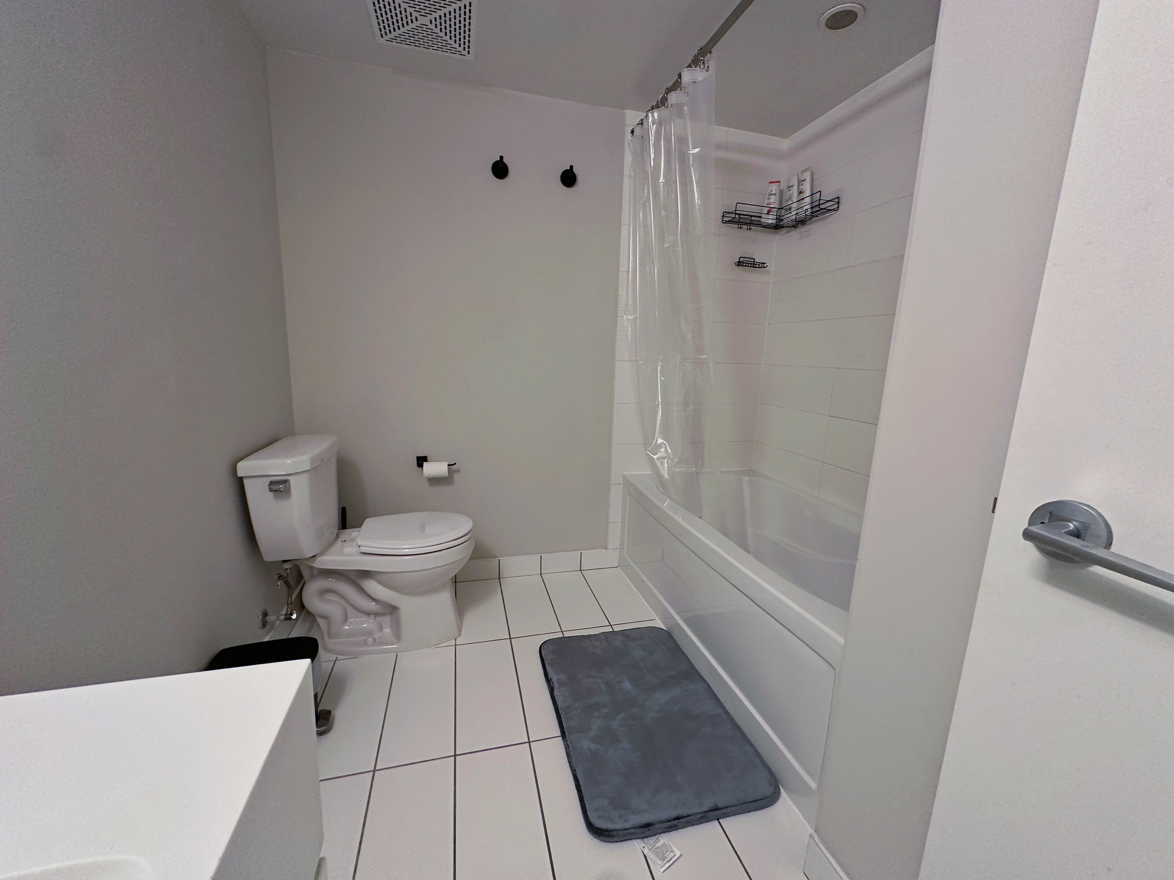 A small, modern bathroom with a toilet, a shower with a glass door, and a white sink.