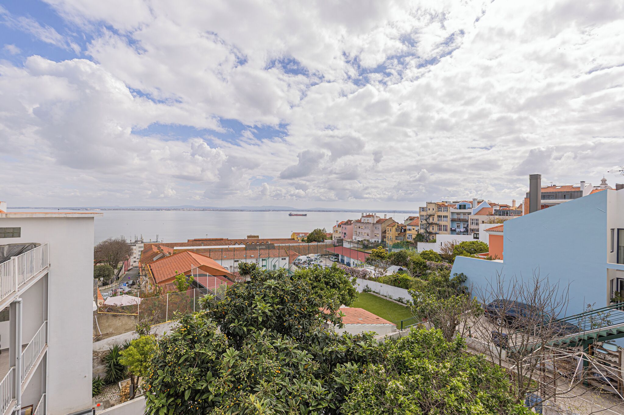 A coastal cityscape with buildings, a body of water, and a ship in the distance.