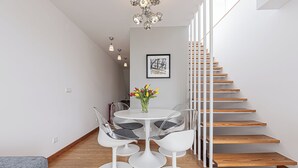 A modern interior with a staircase, a dining area with a round table and chairs, and a framed picture on the wall. - Barbadinhos Apartments in Lisbon Historic (Lisbon)