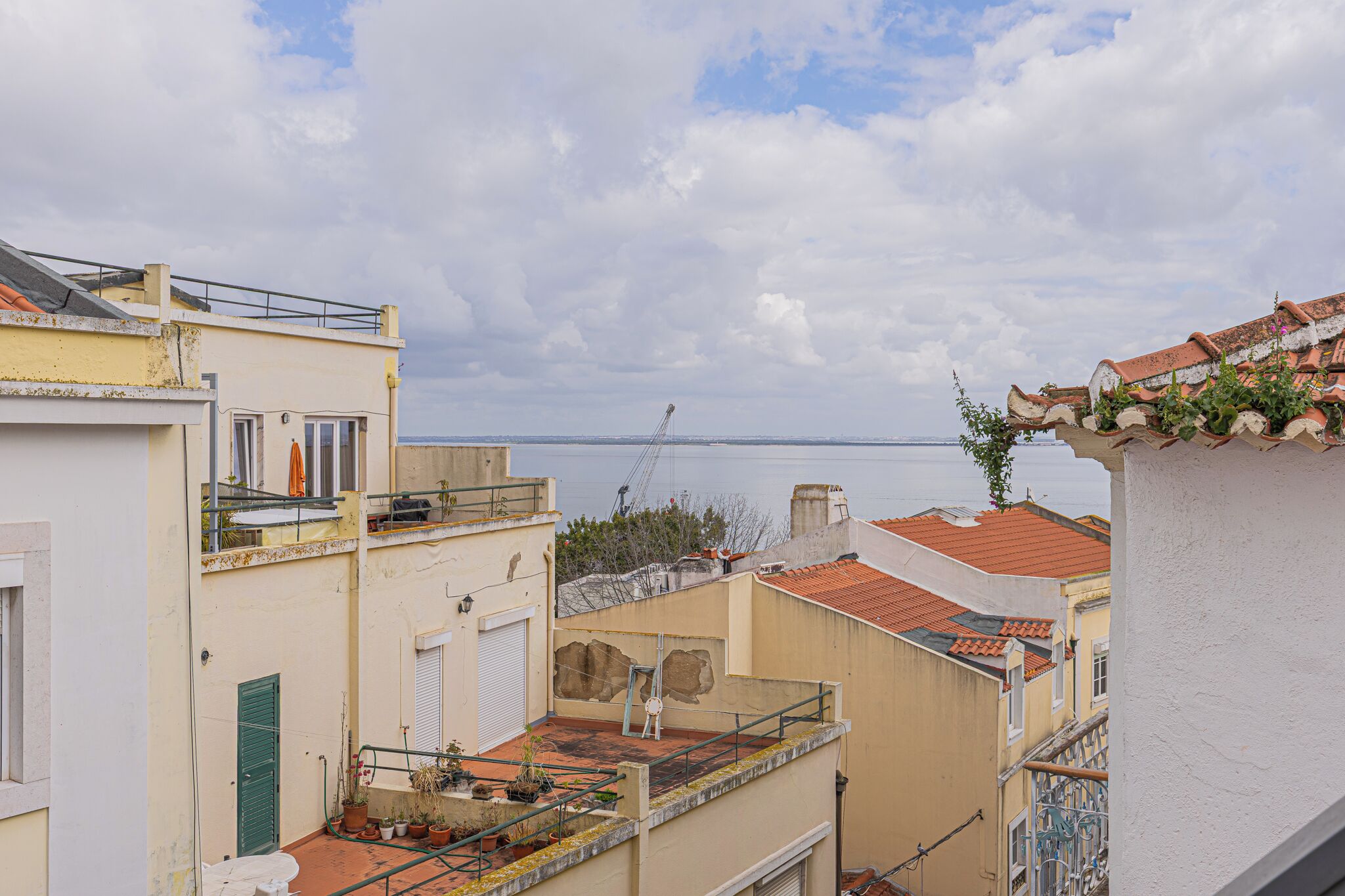 A coastal residential area with buildings, a crane, and a view of the sea.