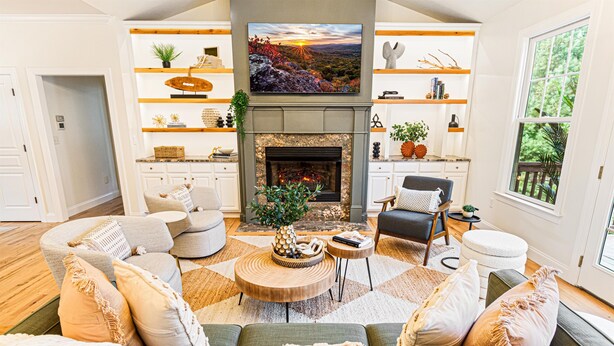 A spacious living room with a fireplace, comfortable seating, and a large TV mounted above it. - Resort-style home w/ heated pool, hot tub, arcade (Fletcher)