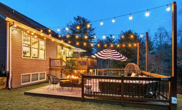 A wooden deck with outdoor furniture, string lights, and a covered seating area.