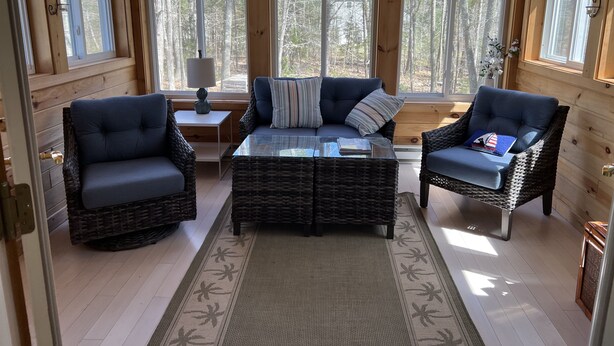 A cozy cabin interior with wicker furniture, large windows, and a view of the forest. - Create Memories only 10 min walk to Long Sands beach. (York)