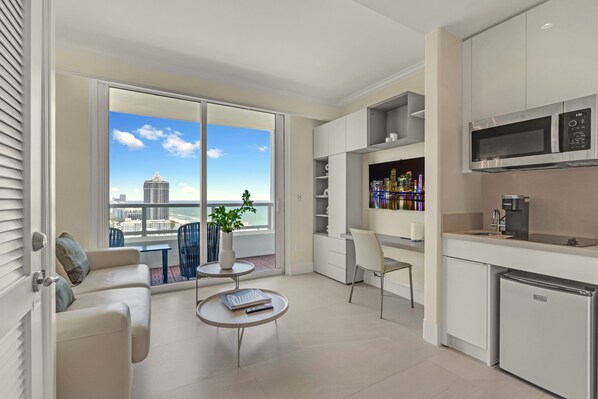 A modern apartment with a balcony, a kitchenette, and a seating area with a view of the city. - Jr Suite Presidential Design Ocean Fontainebleau (Miami Beach)