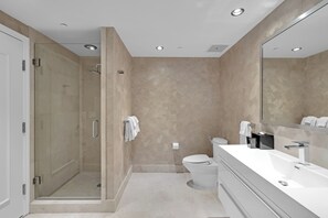 A modern bathroom with a walk-in shower, a toilet, and a large mirror. - Jr Suite Presidential Design Ocean Fontainebleau (Miami Beach)