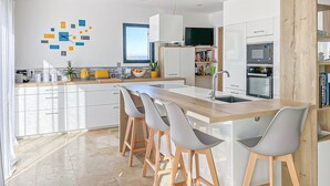 A modern kitchen with a central island, bar stools, a built-in oven, and a microwave. - Gorgeous home in Rochegude with private swimming pool, can be inside or outside (Rochegude)