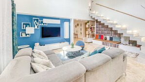 A modern living room with a large grey sofa, a flat-screen TV, and a bookshelf. - Gorgeous home in Rochegude with private swimming pool, can be inside or outside (Rochegude)