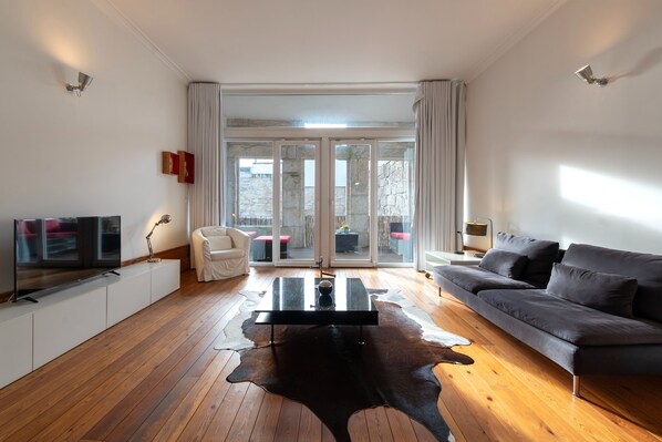 Un salon moderne avec un téléviseur à écran plat, un pouf en cuir, un canapé et une table basse.