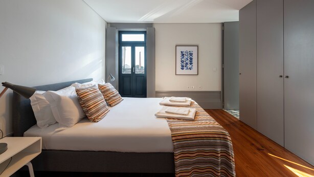 Un dormitorio moderno con una cama grande, una mesita de noche, un armario y una obra de arte enmarcada en la pared.