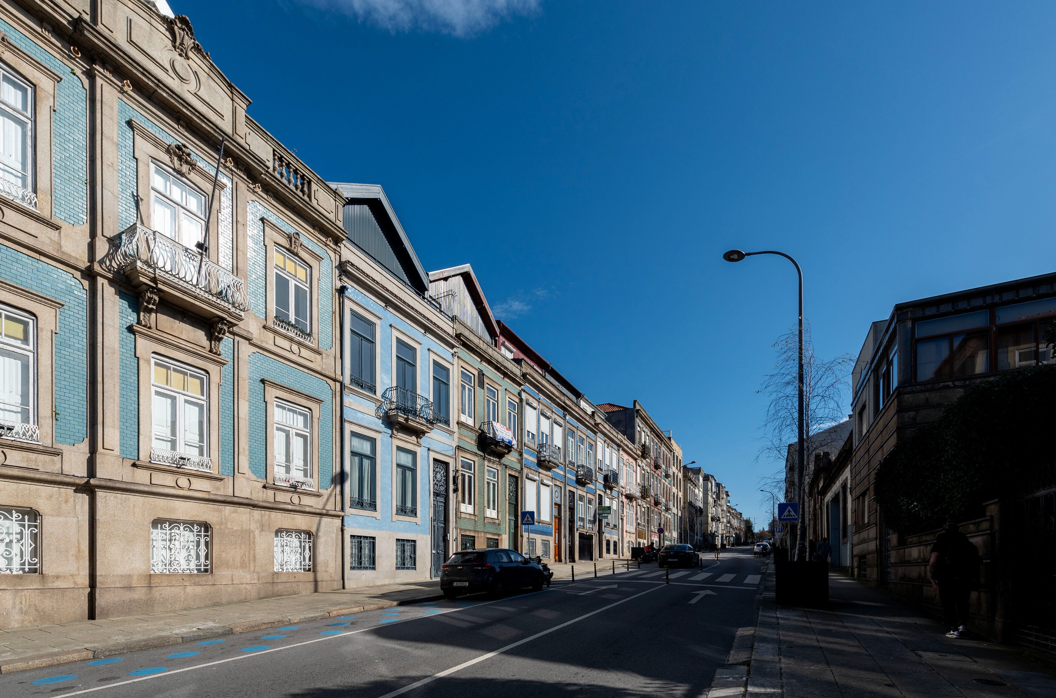 Una calle bordeada de edificios históricos, cielo azul despejado y automóviles estacionados.