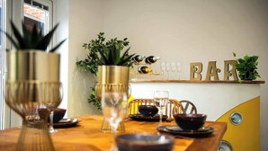 A dining table set with glassware and dishes, a plant in a gold pot, and a vintage yellow chair. - Amazing City Centre Home  (Derby)
