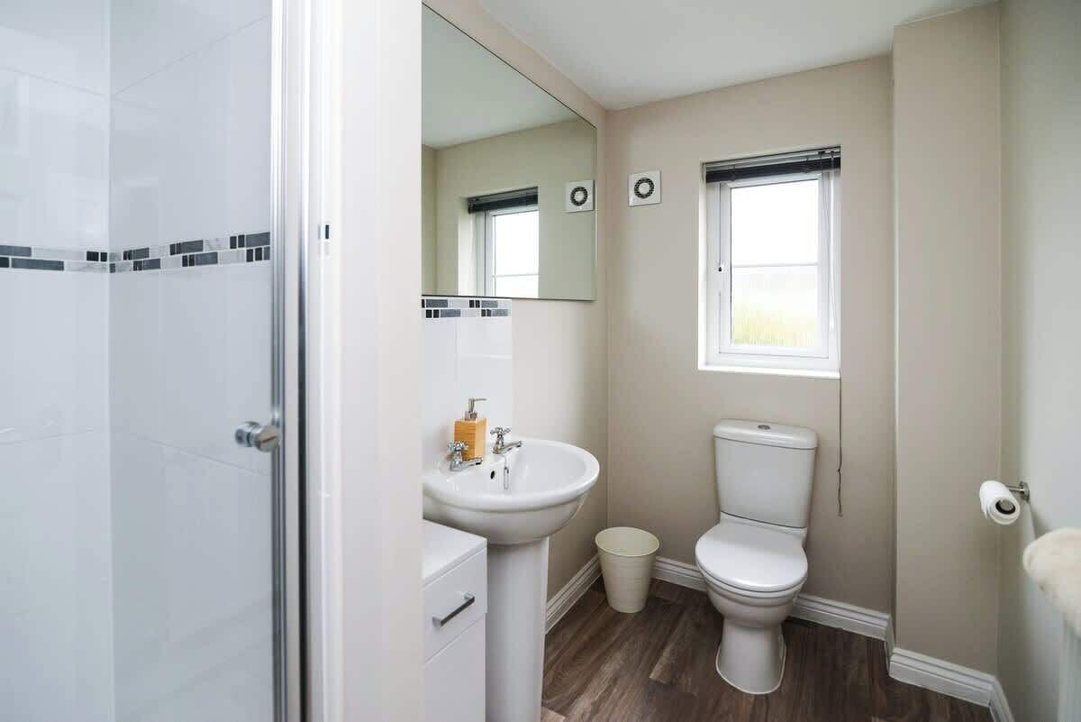 Une salle de bain avec une douche, un lavabo, des toilettes et une fenêtre.