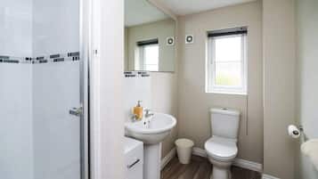Une salle de bain avec une douche, un lavabo, des toilettes et une fenêtre.