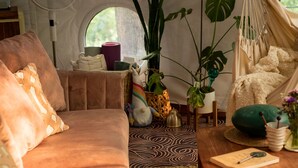 Een gezellig ingericht tentinterieur met een bank, een tafel en diverse planten.