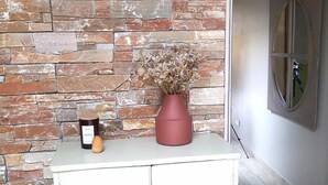 A white cabinet with a vase of dried flowers and a bottle of wine on top.