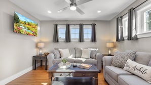 A modern living room with a ceiling fan, a sofa set, a coffee table, and a painting on the wall.