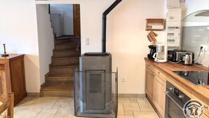 Une cuisine équipée d’un poêle à bois, d’un escalier et d’un plan de travail avec des appareils électroménagers.