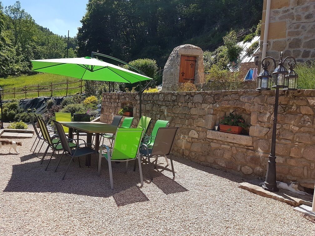 Een terras met een tafel en stoelen, een stenen muur en een houten deur.