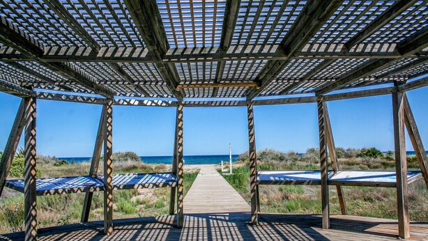 A wooden gazebo with a view of the beach and ocean.
