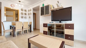 A modern living room with a TV, wooden furniture, and decorative plates on the wall.
