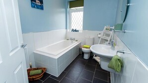A bathroom with a bathtub, toilet, sink, and a small window with a 'Relax' sign. - Captivating 2-bed House in Chesterfield (Chesterfield)