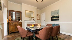 A dining area with a marble table, four brown chairs, a green rug, a wooden cabinet, and a fireplace. - Captivating 2-bed House in Chesterfield (Chesterfield)