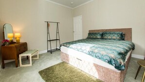 A bedroom with a bed, a nightstand, a dresser, a mirror, a hanging rack, and a small stool. - Captivating 2-bed House in Chesterfield (Chesterfield)
