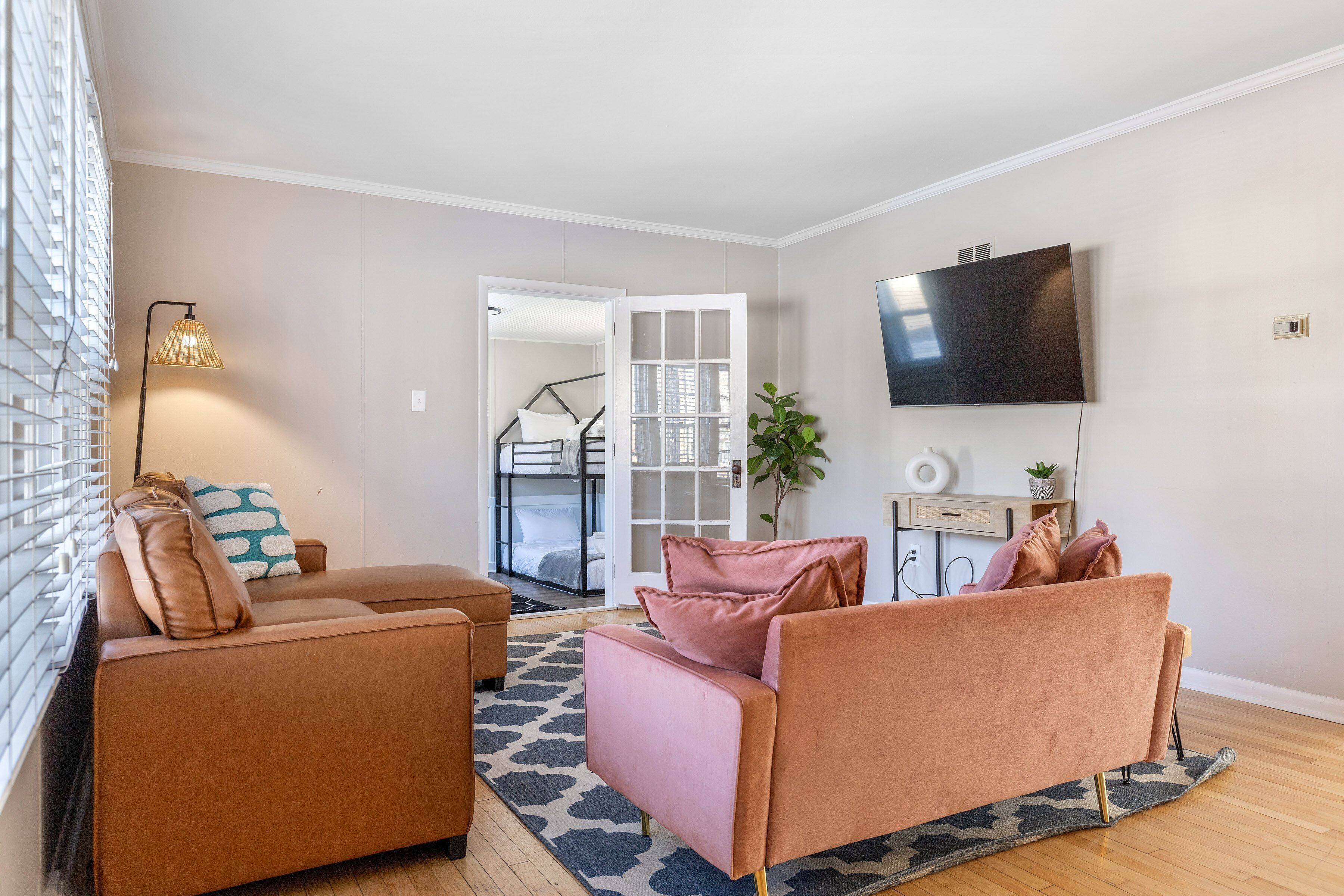 A modern living room with a sofa set, a flat-screen TV, and a patterned rug.