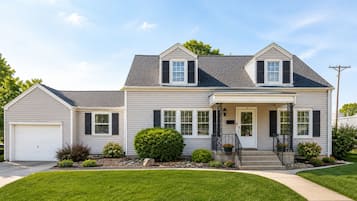 A two-story house with a garage, a front porch, and a well-maintained lawn.