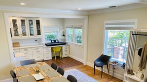 Une cuisine moderne avec des meubles blancs, une table à manger en bois agrémentée de sets de table et une chaise jaune vif.