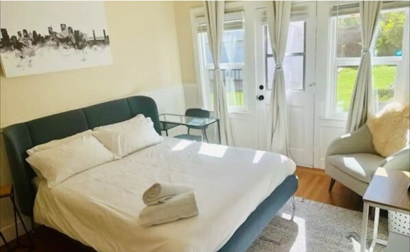 A bedroom with a bed, a chair, a table, and a window with curtains. - Bebedeux - Charming & Clean Classic in the Fab 40s
(Sacramento)