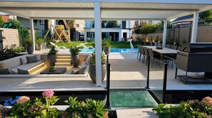 Patio esterno coperto con piscina, zona relax e angolo barbecue.