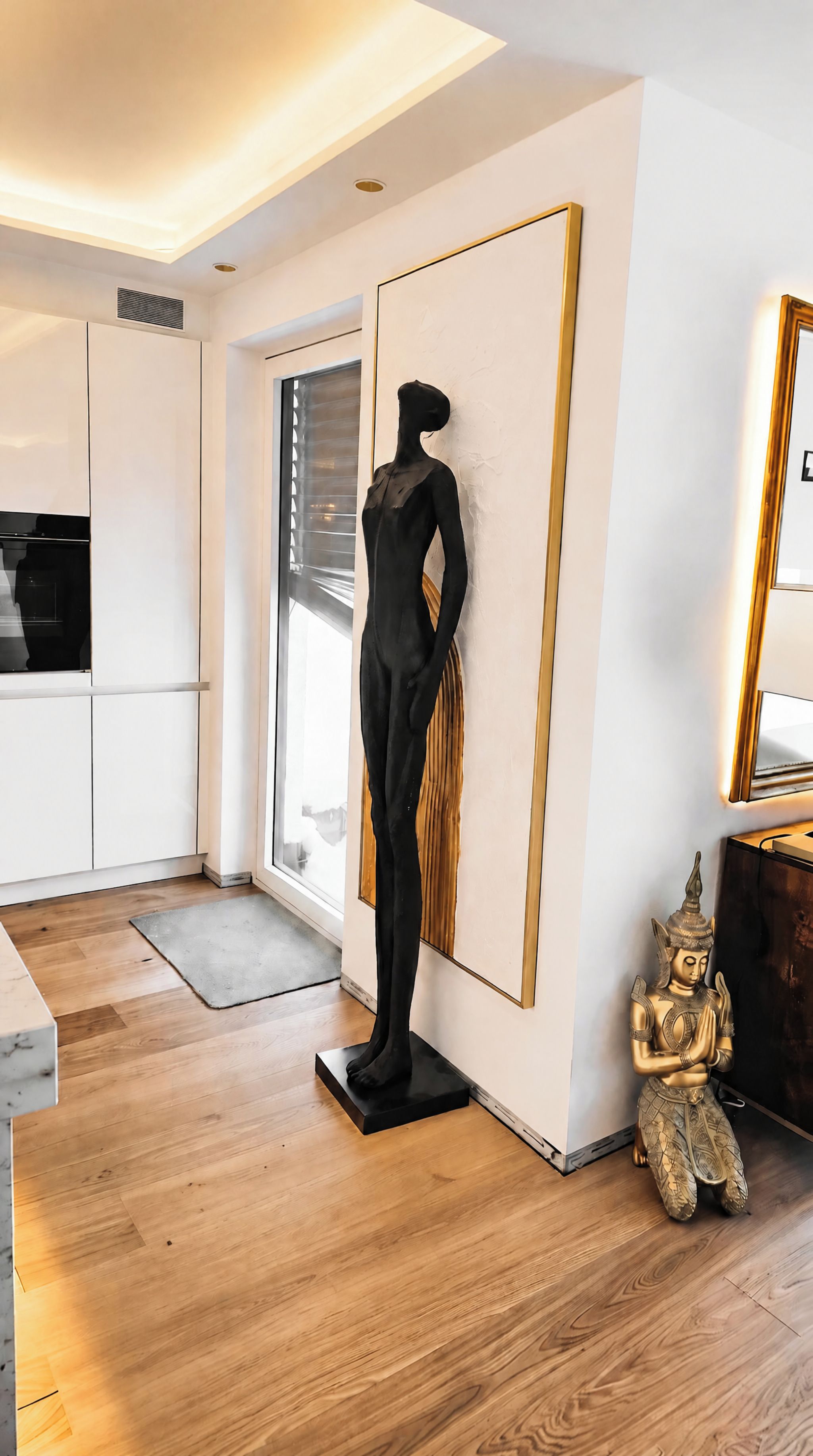 Ein modernes Interieur mit einer Passionsfigur, einer Buddha-Statue und einem großen Spiegel.