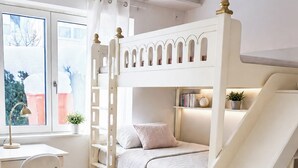 Een kinderkamer met een stapelbed, bureau, stoel en een klein boekenrek.