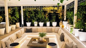 A modern lounge area with a sofa, coffee table, and potted plants.
