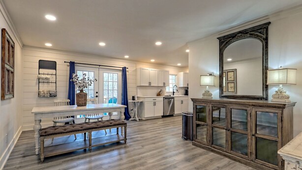 A spacious kitchen with white cabinetry, a dining area with a bench, and a large mirror above a wooden cabinet. - Newly Renovated Ranch Overlooking Active Pasture (Clarkesville)