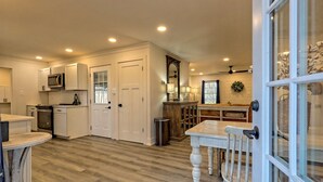A spacious kitchen with white cabinetry, a microwave, and a dining area with a wooden table and chairs. - Newly Renovated Ranch Overlooking Active Pasture (Clarkesville)