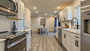 A modern kitchen with white cabinets, stainless steel appliances, and a wooden floor. - Newly Renovated Ranch Overlooking Active Pasture (Clarkesville)