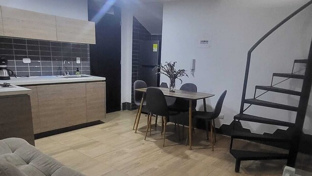 A modern kitchen with a dining area, a staircase, and a sofa. - 1. Tranquilo Apartamento Duplex - Carrera 23 C 69 -10 Manizales Caldas. Colombia (Manizales)