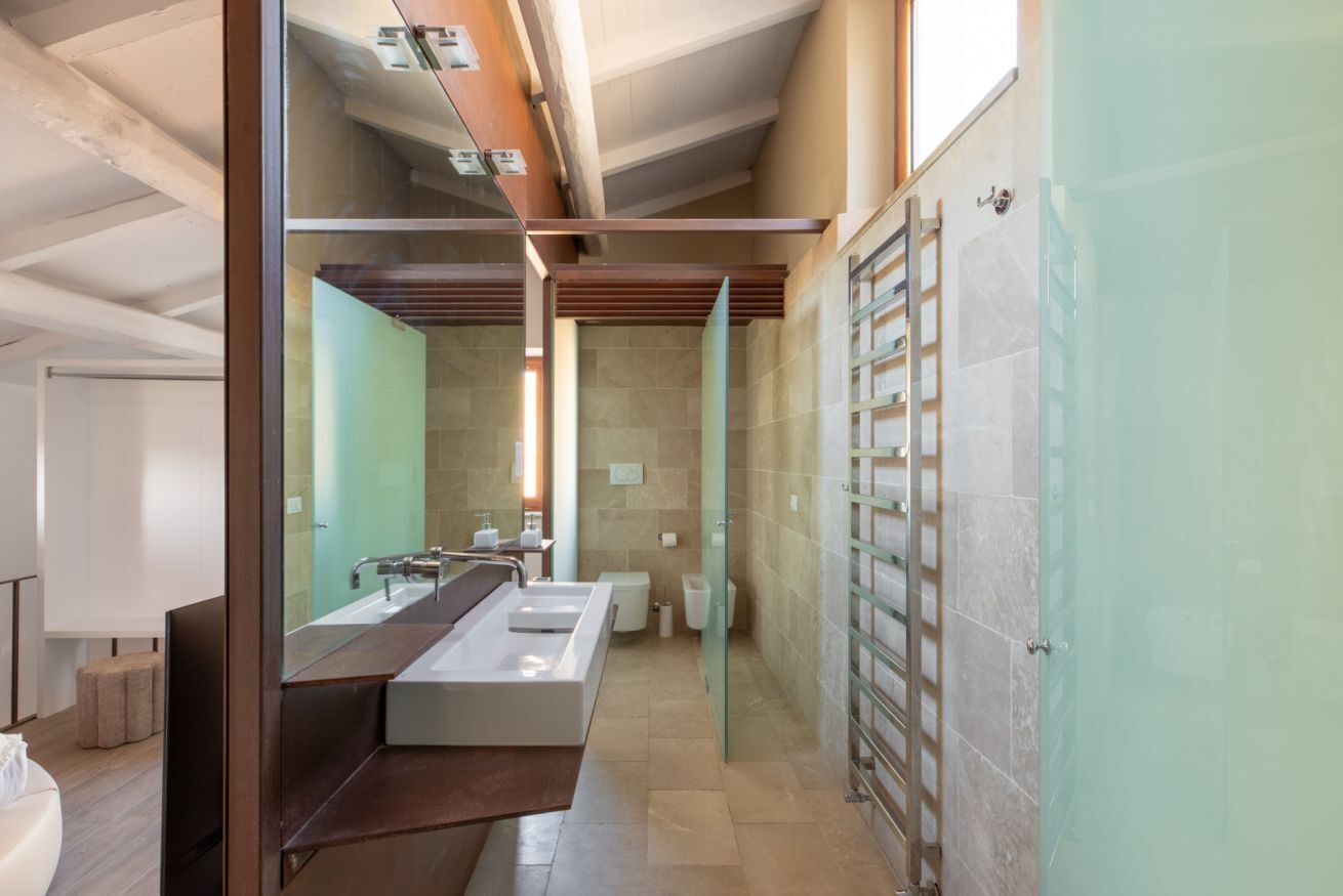 A modern bathroom with a large mirror, two sinks, and a glass shower enclosure.