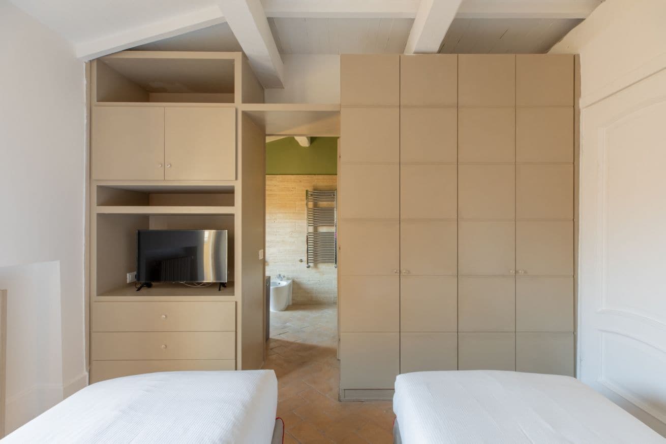 Una camera da letto con due letti, un armadio e una televisione.