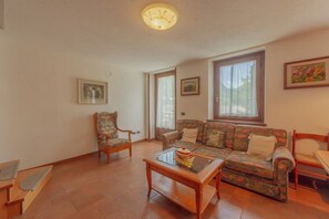 Una sala de estar con sofá, sillones, una mesa de centro y una lámpara de techo.