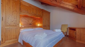 A wooden-paneled bedroom with a bed, a chair, and a small table. -  CHALET PONTAL 5 - Relax with a beautiful view of the mountains (Courmayeur)