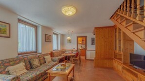 A living room with a sofa, coffee table, and a TV on a wooden cabinet. -  CHALET PONTAL 5 - Relax with a beautiful view of the mountains (Courmayeur)