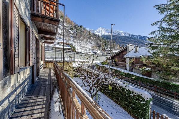 A wooden balcony with a view of snow-covered mountains.