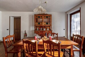 A dining room with a wooden table set for six, a wooden cabinet with glass doors, and a chandelier.