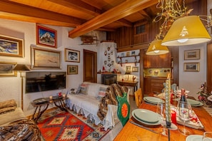 A cozy living room with a sofa, a TV, a fireplace, and a dining area with a table set for two.